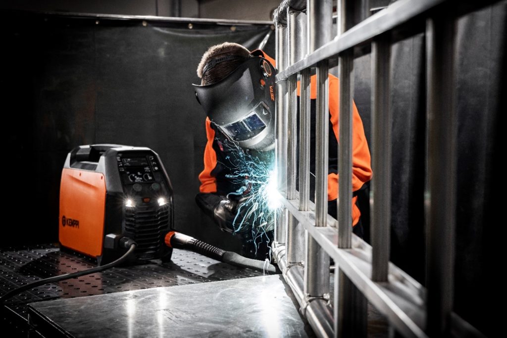 In the picture, a welder is welding with the Kemppi Master M 205 MIG/MAG welding machine.