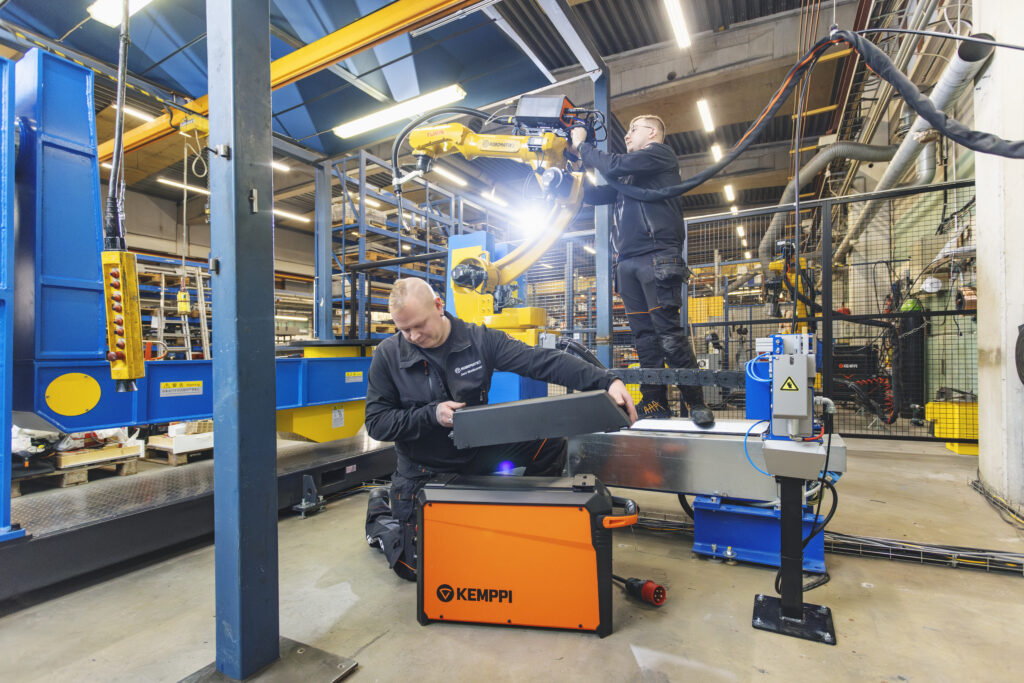 In this photo the managing director Jani Matikainen with his colleague is integrating a Kemppi AX MIG Welder to a robot.